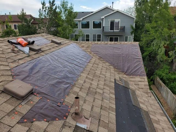 Roof repair in progress with waterproof tarp covering damaged shingles - professional roofing service