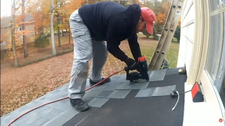 Vent Pipe Flashing Leak Repair specialist installing new shingles with pneumatic nail gun on residential roof